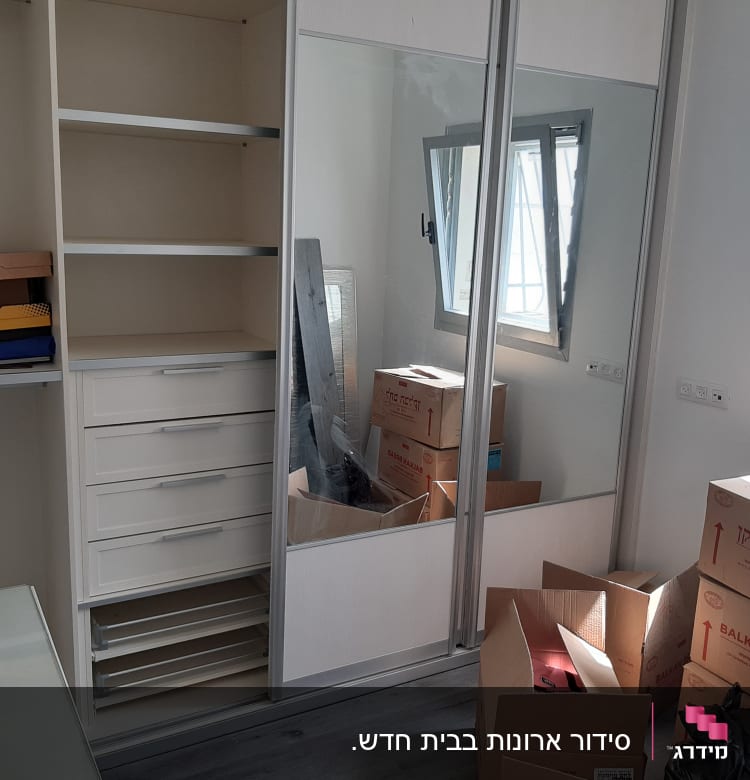 ארון עם מדפים ומגירות, קופסאות קרטון על הרצפה